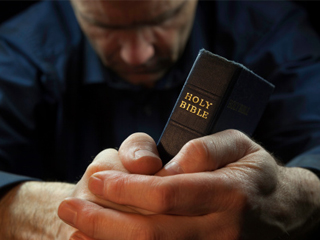 praying man holding bible