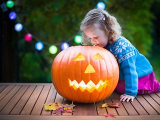 Little girl looking at a jack o lantern 